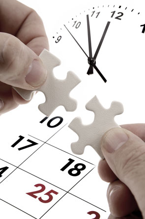 Mains tenant deux pièces de puzzle correspondantes devant une horloge et un calendrier.